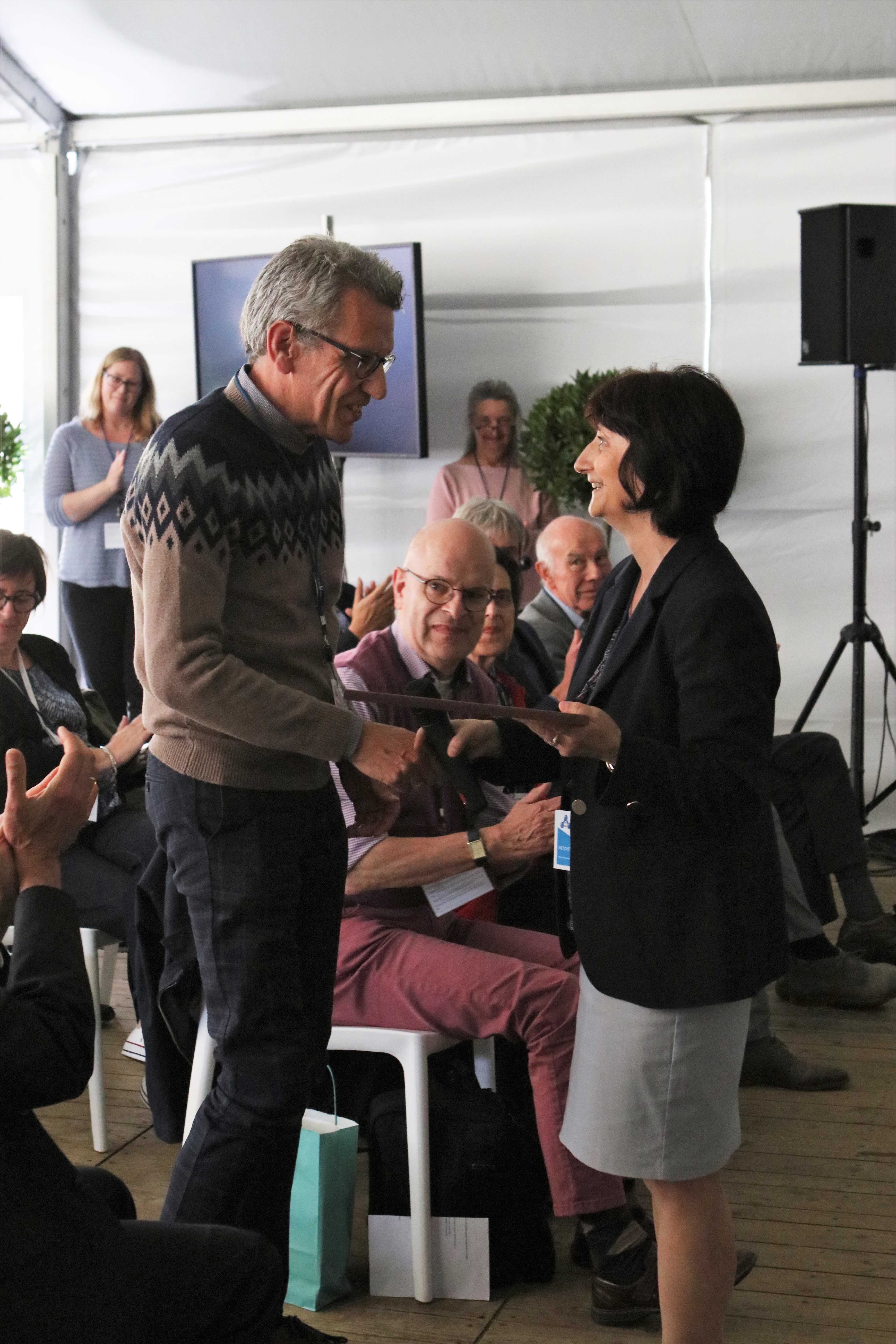 Uitreiking van het certificaat door Stoyka Netcheva van de WMO aan Hugo De Backer, hoofd van de Dienst Weerinstrumenten van het KMI.